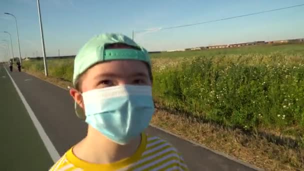 Dziewczyna z maską na twarzy biegająca po drodze — Wideo stockowe