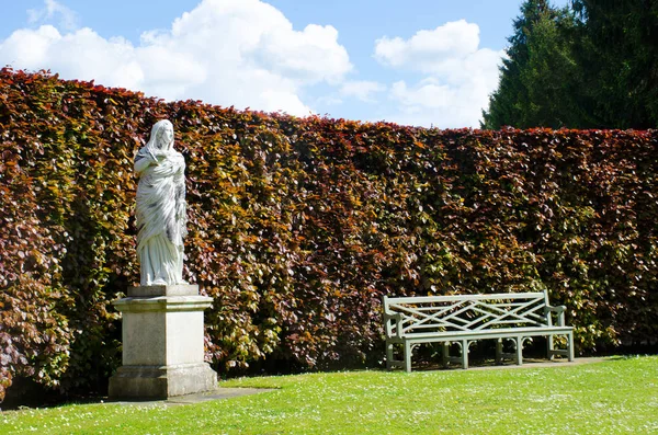 Estátua com banco no jardim de campo inglês formal — Fotografia de Stock