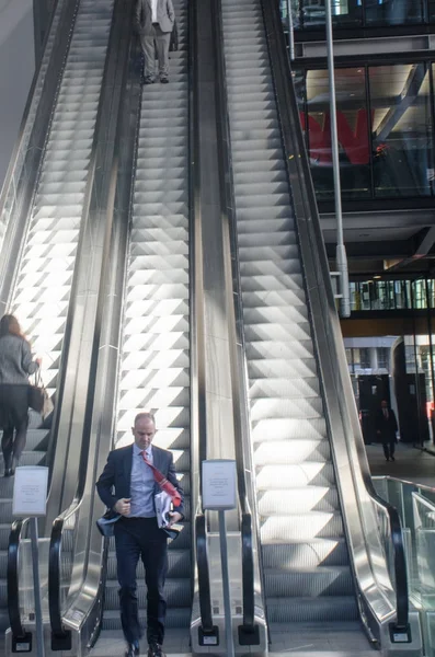 Dynamické Britské obchodní muž ve spodní části eskalátoru — Stock fotografie