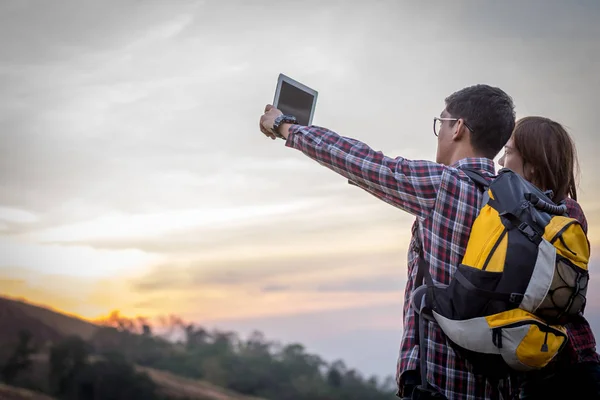 Tourists look at a map on the tablet on mountain. Royalty Free Stock Images