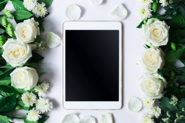 Taze beyaz gül çiçek ve beyaz zemin üzerine tablet