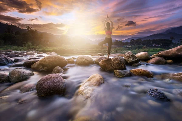 Mujer joven haciendo yoga en la roca en la mañana —  Fotos de Stock
