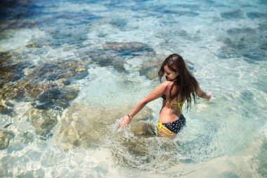 Asya kadın denizde oynarken bikini giyiyor