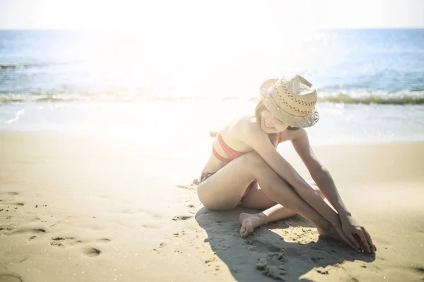 Sahilde oturan kırmızı bikini giyen genç kız.