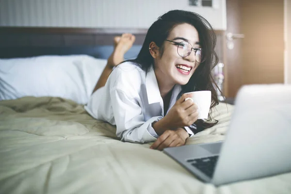Feliz mujer de asia trabajando en la cama con el ordenador portátil en el dormitorio . —  Fotos de Stock