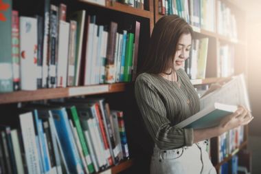Genç kadın librar içinde kitap ve stand açık bookshelf okuma
