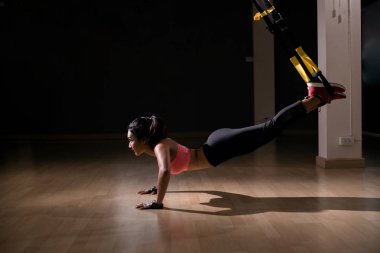 Güçlü kadın trx egzersiz fitness salonunda askıları ile yapmak.