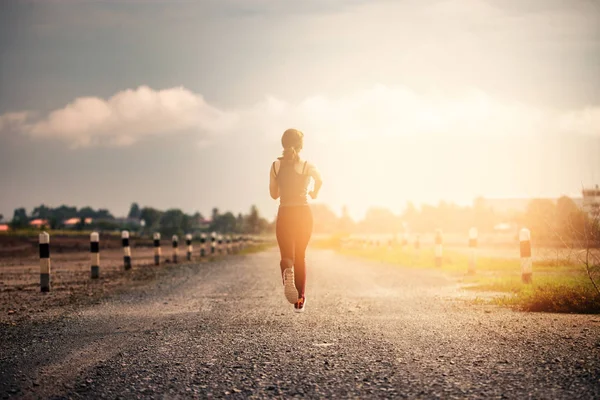Joven mujer de fitness corriendo en la carretera por la mañana . —  Fotos de Stock