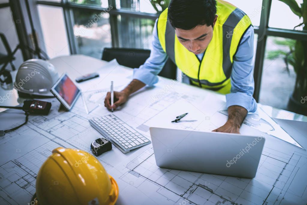Architect working on blueprint.engineer inspective in workplace - architectural project, blueprints,ruler,calculator,laptop and divider compass. Construction concept. Engineering tools, working concept.