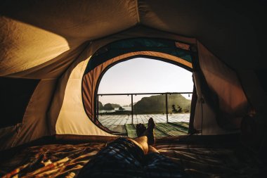 Çadır kamp üzerinden manzaralı uyandığımız dağlarda bir çadırda yatan bir adam göster.