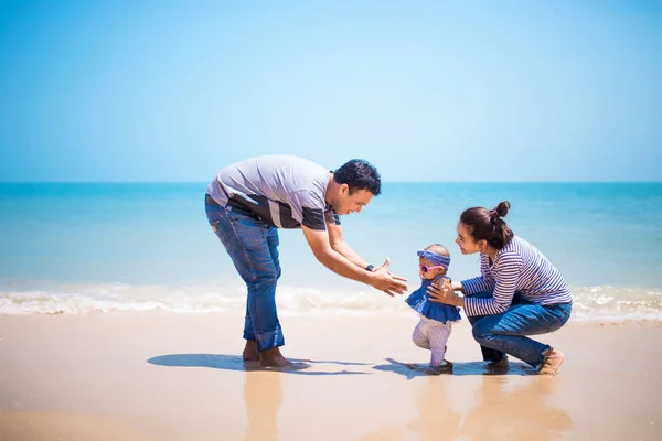 Asia parents playing with daughter at the sea.