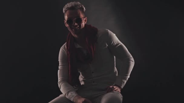 Retrato de un hombre con una bufanda roja sobre un fondo oscuro — Vídeos de Stock