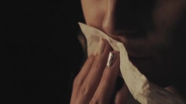 Dudaklarındaki kırmızı ruj makyajını dikkatlice silip temizleyen bir kadın.