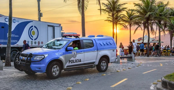 26 Novembro 2016. Carro de polícia no fundo do belo pôr-do-sol com o sol laranja na praia de Ipanema, Rio de Janeiro, Brasil — Fotografia de Stock