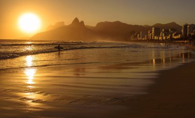 Ipanema Plajı'nda ipe Irmaos dağ ve sörfçü siluet ile altın günbatımı