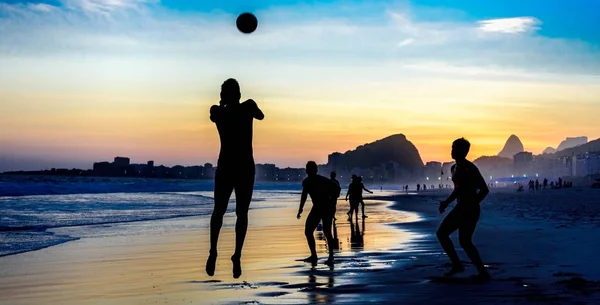 Silueta de hombre saltando jugando fútbol de playa en el fondo de la hermosa puesta de sol en la playa de Copacabana, Río de Janeiro — Foto de Stock