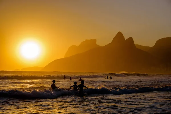 Siluetas no identificables disfrutando de los rayos del sol de la tarde en la playa de Ipanema — Foto de Stock