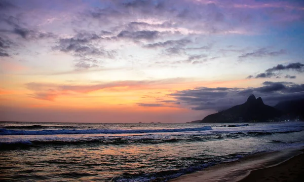 Silueta de Dois Irmaos Montaña, hermoso cielo de puesta de sol y reflejo del cielo en el océano Atlántico en la playa de Ipanema — Foto de Stock