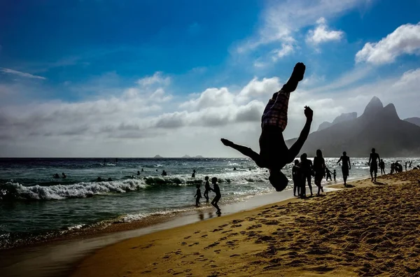 Silhouette de l'homme parfumant un saut périlleux dans le dos en position de brochet à la plage d'Ipanema, Rio de Janeiro, Brésil — Photo