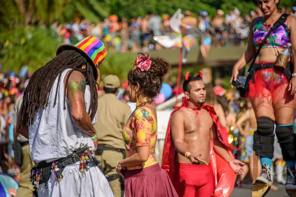 Casal de homem com dreadlocks e mulher jovem no fundo do homem embaçado em traje do diabo e mulher andando sobre palafitas — Fotografia de Stock