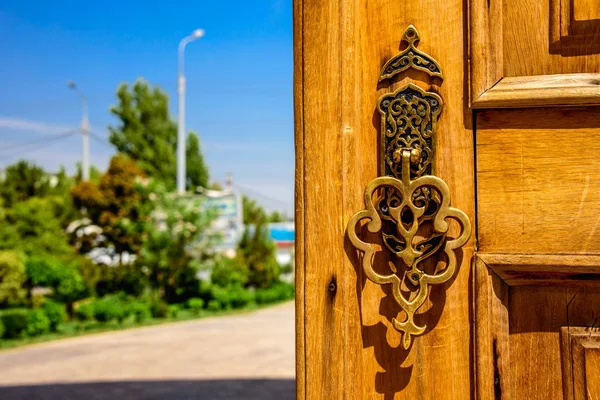Güneşli yaz günü Hazreti Imam Ensemble Taşkent merkezi şehrin içinde ahşap kapıda altın oymalı tutamacı