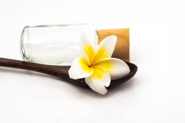 Frangipani tahta kaşık ve bir şişe beyaz backg üzerinde