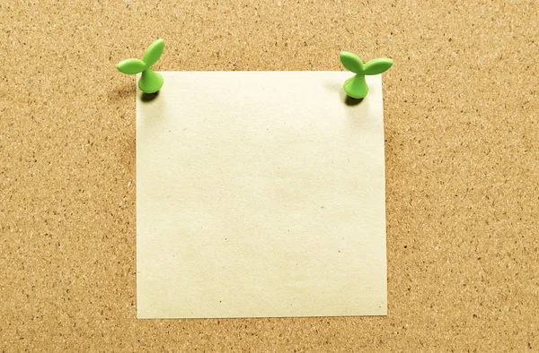 Blank yellow square note paper on cork board with leaf pin