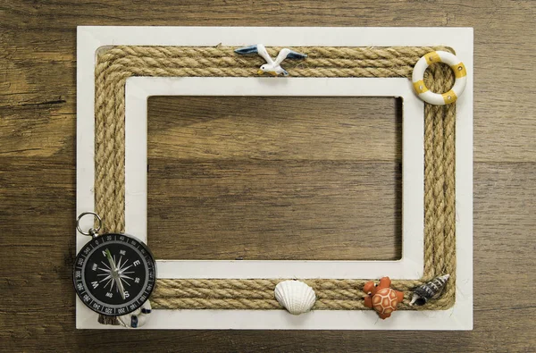 木制相框与绳索装饰在木桌上与指南针在左角落在下面 — 图库照片