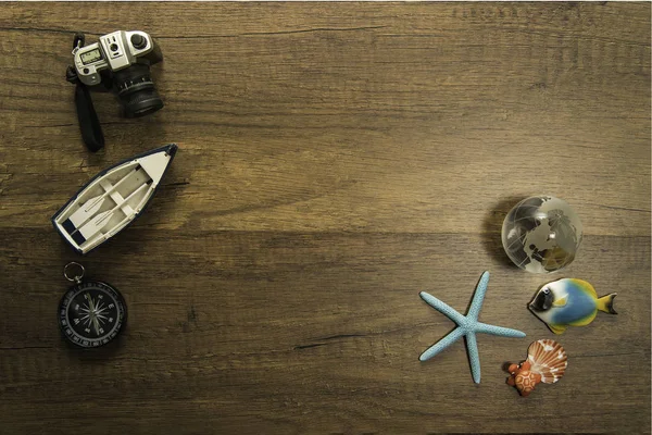 Camera boat and compass decorate on wooden table with starfish world glass marble and turtle