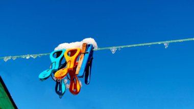 Kar ve buzla kaplı giysileri kurutmak için renkli mandallar.