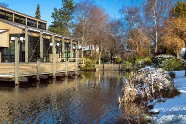 Erlier bahar zaman güneş, yeşil ağaçlar ve kar. Bir su birikintisi yakın güzellikte bir konumda yer alan konut.