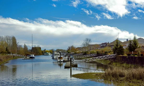 温哥华郊区风景如画的村庄 沿着一排的房子 在一个蓝天的背景下 在码头上流淌着一条河流 游艇和小船 — 图库照片