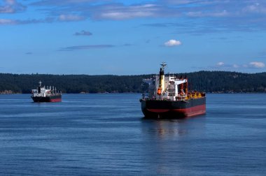 Vancouver harbor, ocean tankers waiting for loading in port white waves in a sunny day on the background scenery of blue sky