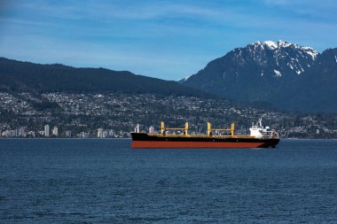 Vancouver limanı, Batı Vancouver, okyanus tankeri güneşli bir günde Batı Vancouver şehrinin arka planında ve karla kaplı dağ manzarasında yükleme için bekliyor.