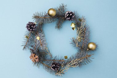 Noel çelengi şeklinde düz bir beste. Mavi ladin dalları, koniler, mavi arka planda oyuncaklar. Noel, kış, yeni yıl konsepti. Üst görünüm, metin için boşluk kopyala.