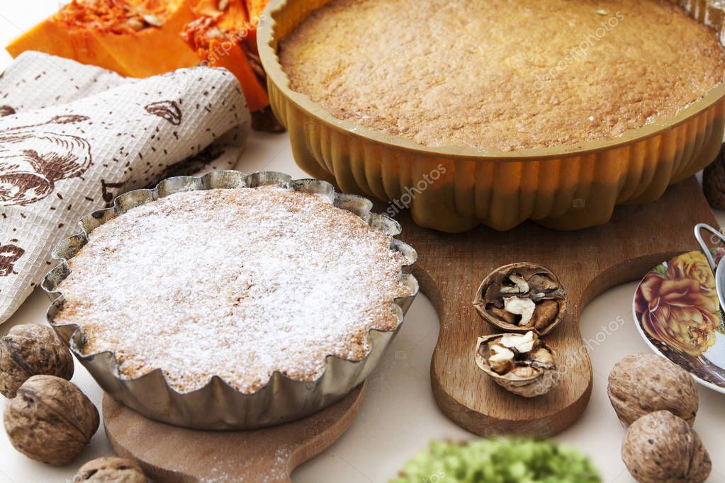Pumpkin pies in a baking dish. There are nuts on the table. Autumn food, pastries.
