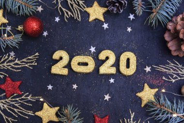 Yeni yıl 2020 'de yaşandı. Karanlık bir arka planda, 2020 altın gibi parlak sayılar parıltı, ladin dalları, Noel oyuncakları ve bir çelenk..