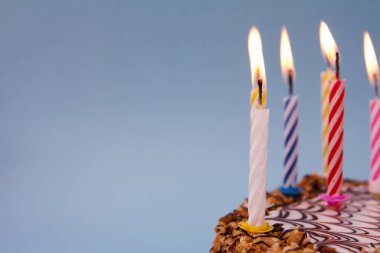 Mavi arka planda mumları olan kutlama pastası..