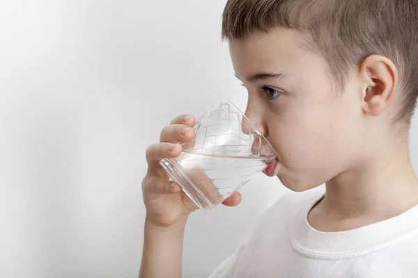 The boy drinks water from a glass. The concept of pure water Royaltyfria Stockfoton