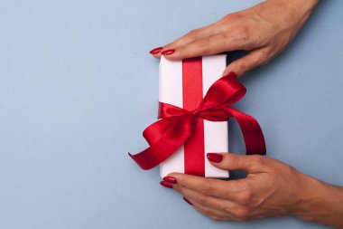 Mavi arka planda kadın eli hediyesi. Kırmızı kutulu beyaz kutu 