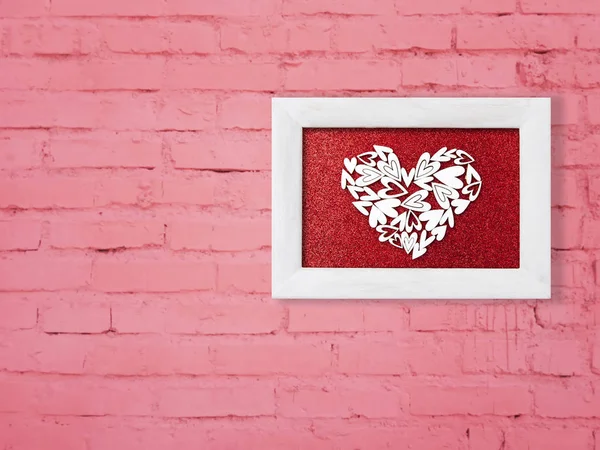 Marco blanco con un corazón en una pared de ladrillo rosa. Antecedentes —  Fotos de Stock