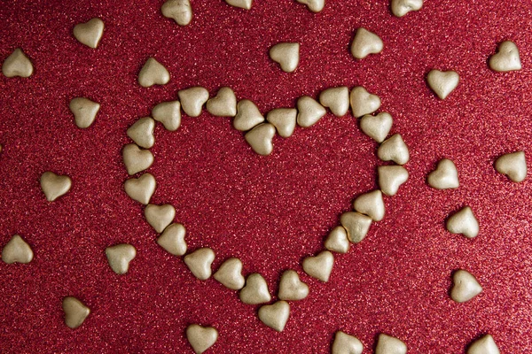 Καρδιά σχήμα από μικρές καρδιές σε ένα κόκκινο φόντο glitter. Α — Φωτογραφία Αρχείου