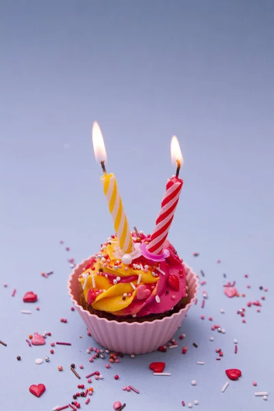 Cupcake con crema y dos velas y un polvo con corazones en un —  Fotos de Stock