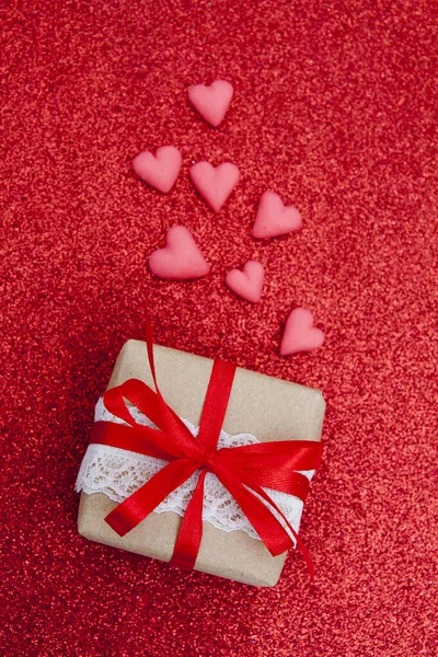 Caixa de presente e corações em um fundo de brilho vermelho. Flat lay Valente — Fotografia de Stock