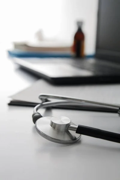 Doctors workplace: close up stethoscope, defocused laptop, documents, pens. Medical concept — 스톡 사진