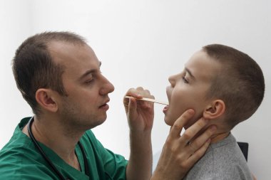 Doktor bir çocuğun boğazına bakar. Hastalıklar ve tedaviler