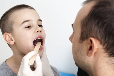 Doktor bir çocuğun boğazına bakar. Hastalıklar ve tedaviler