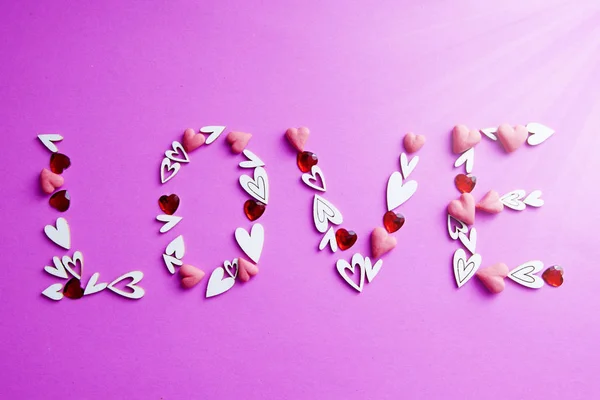Λέξη Αγάπη φτιαγμένη από καρδιές στον ήλιο σε ροζ φόντο. Έννοια για την ημέρα του Αγίου Βαλεντίνου, ημέρα του γάμου — Φωτογραφία Αρχείου