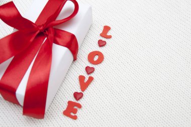 Aşk ve Beyaz Hediye Kutusu. Beyaz örgü üzerinde kırmızı bir fiyonk.