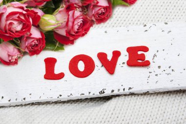 Yazı kırmızı harflerle yazılmış, ahşap bir yüzeye yazılmış.